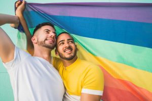 gay-couple-embracing-showing-their-love-with-rainbow-flag-img